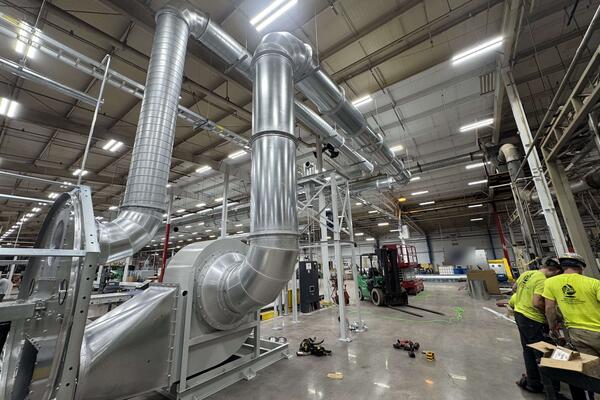 Engineered Recycling Systems crew installing a dust collection system, with blower unit, spiral ducting and overhead transfer lines running through the plant.
