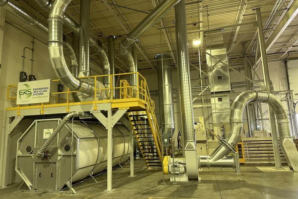 CCM OCT filter system installed under a yellow-railed platform, with blower, cyclone and spiral ducting running through a corrugated plant.
