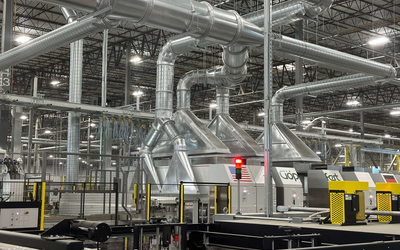 ERS dust collection hoods installed above a GOPFERT die cutter, connected to the CCM® OCT Filter system for efficient scrap and dust removal.