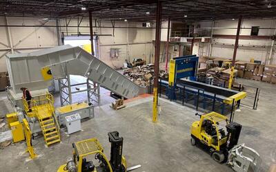 Cardboard baler ejecting a dense, wire-bound bale at Engineered Recycling Systems facility, showcasing high-capacity scrap compaction