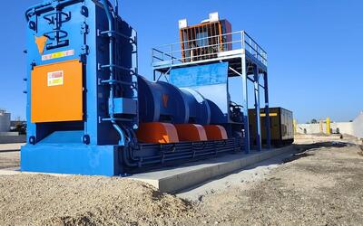 Blue TAURUS shear baler installed on a scrap yard, with the operator cabin on a raised platform behind the machine
