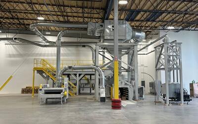 A complete scrap handling and dust collection system installed in a new corrugated plant, with the filter on its access platform, overhead duct runs, shredder, baler and separator tower