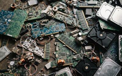 Mixed electronic scrap for recycling - circuit boards, RAM, hard drives, small motors, power supplies and cable on a concrete floor