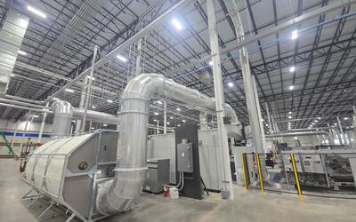 Engineered Recycling Systems CCM® OCT Filter installed in a corrugated manufacturing facility, showcasing 2025 model with modular segments, rotating anti-static suction nozzles, and positive-pressure airflow for high-efficiency dust filtration.