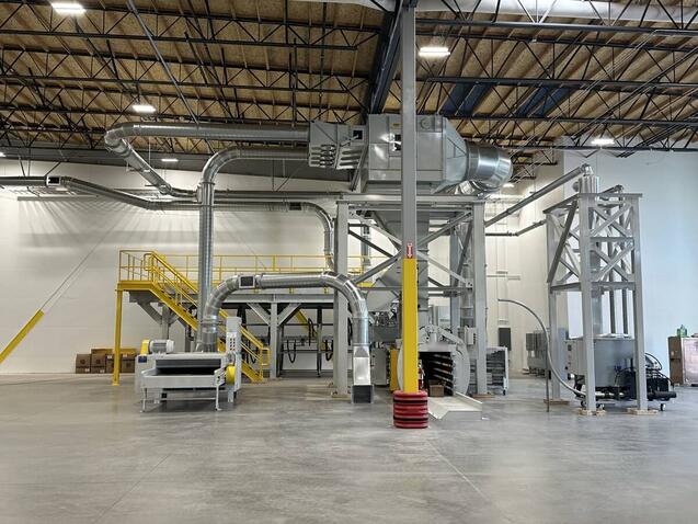 A complete scrap handling and dust collection system installed in a new corrugated plant, with the filter on its access platform, overhead duct runs, shredder, baler and separator tower