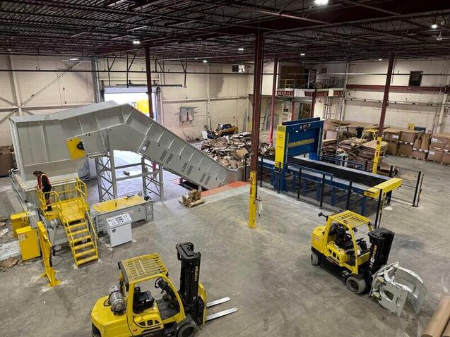 Cardboard baler ejecting a dense, wire-bound bale at Engineered Recycling Systems facility, showcasing high-capacity scrap compaction