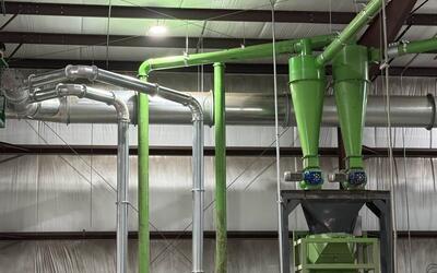 Twin cyclones with rotary airlocks discharging onto a screen, with transfer lines and fans, part of a metals separation line upgraded inside an existing plant