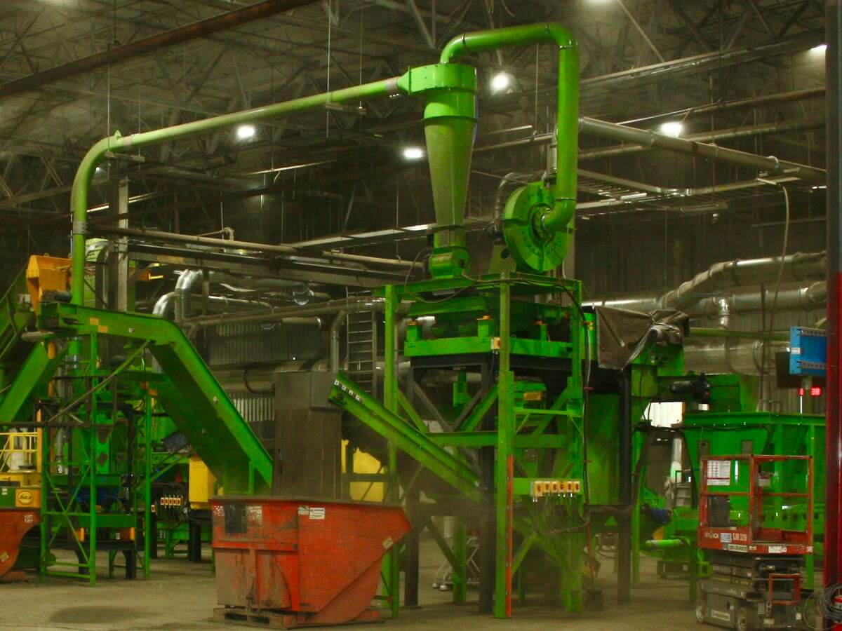 A shredding, milling and separation line installed in a plant, with green machine housings and conveyors between the stages.