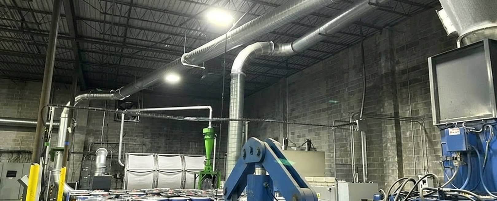 Ductwork rising to a cyclone and filter above a converting hall, with clean filter media in place.